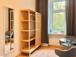 Een kamer met een houten boekenkast, een ronde glazen tafel en een stoel.