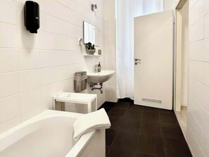 A modern bathroom with a bathtub, a sink, and a toilet. - Servus Homes - Metro Stadthalle - Amadeus (Vienna)