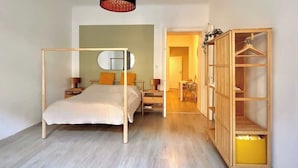 Ein Schlafzimmer mit Himmelbett, Nachttisch, einer Hängeleuchte und einem Holzschrank mit Einlegeböden.