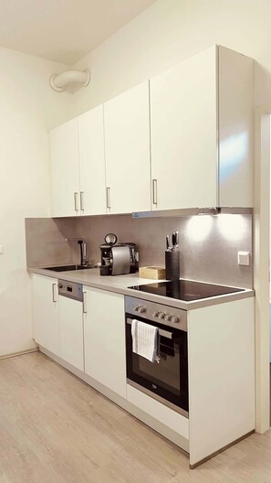A modern kitchen with white cabinets, a stainless steel range, and a built-in oven. - Servus Homes - Metro Stadthalle - Amadeus (Vienna)