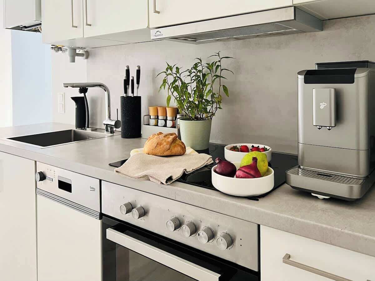 Eine moderne Küche mit Einbauofen, Kaffeemaschine und einem Blumentopf.