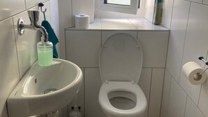 Une petite salle de bain avec des toilettes, un lavabo et une fenêtre.