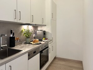 A modern kitchen with stainless steel appliances, a built-in oven, and a countertop with a plant and food items. - Servus Homes - Metro Stadthalle - Vienna Calling (Wien)