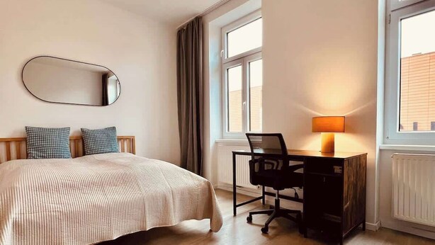 A bedroom with a bed, a desk, a chair, a lamp, and a window. - SOUND OF MUSIC · Servus Homes – Metro Stadthalle – Sound Of Music (Vienna)