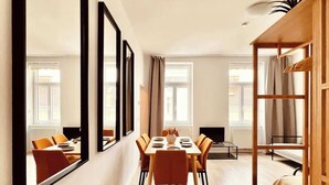 A modern interior with a dining area, large mirrors, and a wooden shelving unit. - SOUND OF MUSIC · Servus Homes – Metro Stadthalle – Sound Of Music (Vienna)