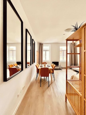 A modern interior with a dining area, large mirrors, and a wooden shelving unit. - SOUND OF MUSIC · Servus Homes – Metro Stadthalle – Sound Of Music (Vienna)
