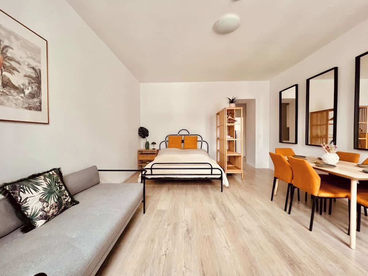 Une chambre moderne comprenant un lit, un canapé, une table à manger avec des chaises et une bibliothèque.
