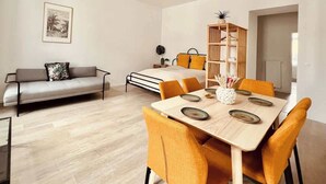 A modern living room with a sofa, dining table, and chairs. - SOUND OF MUSIC · Servus Homes – Metro Stadthalle – Sound Of Music (Vienna)