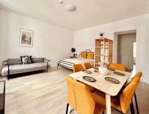 A modern living room with a sofa, dining table, and chairs. - SOUND OF MUSIC · Servus Homes – Metro Stadthalle – Sound Of Music (Vienna)