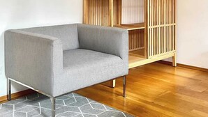Ein modernes Wohnzimmer mit einem Holzregal, einem gemusterten Sofa und einem geometrischen Teppich.