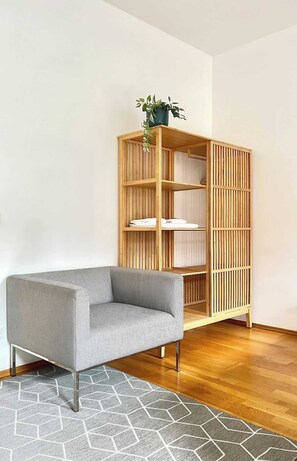 Ein modernes Wohnzimmer mit einem Holzregal, einem gemusterten Sofa und einem geometrischen Teppich.