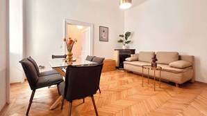 A modern living space with a dining area, sofa, and a herringbone wooden floor. - Servus Homes - rooftop terrace & balcony - Metro (Wien)