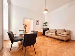 Ein zeitgemäßer Wohnraum mit Essbereich, Sofa und einem Fischgrätparkett.