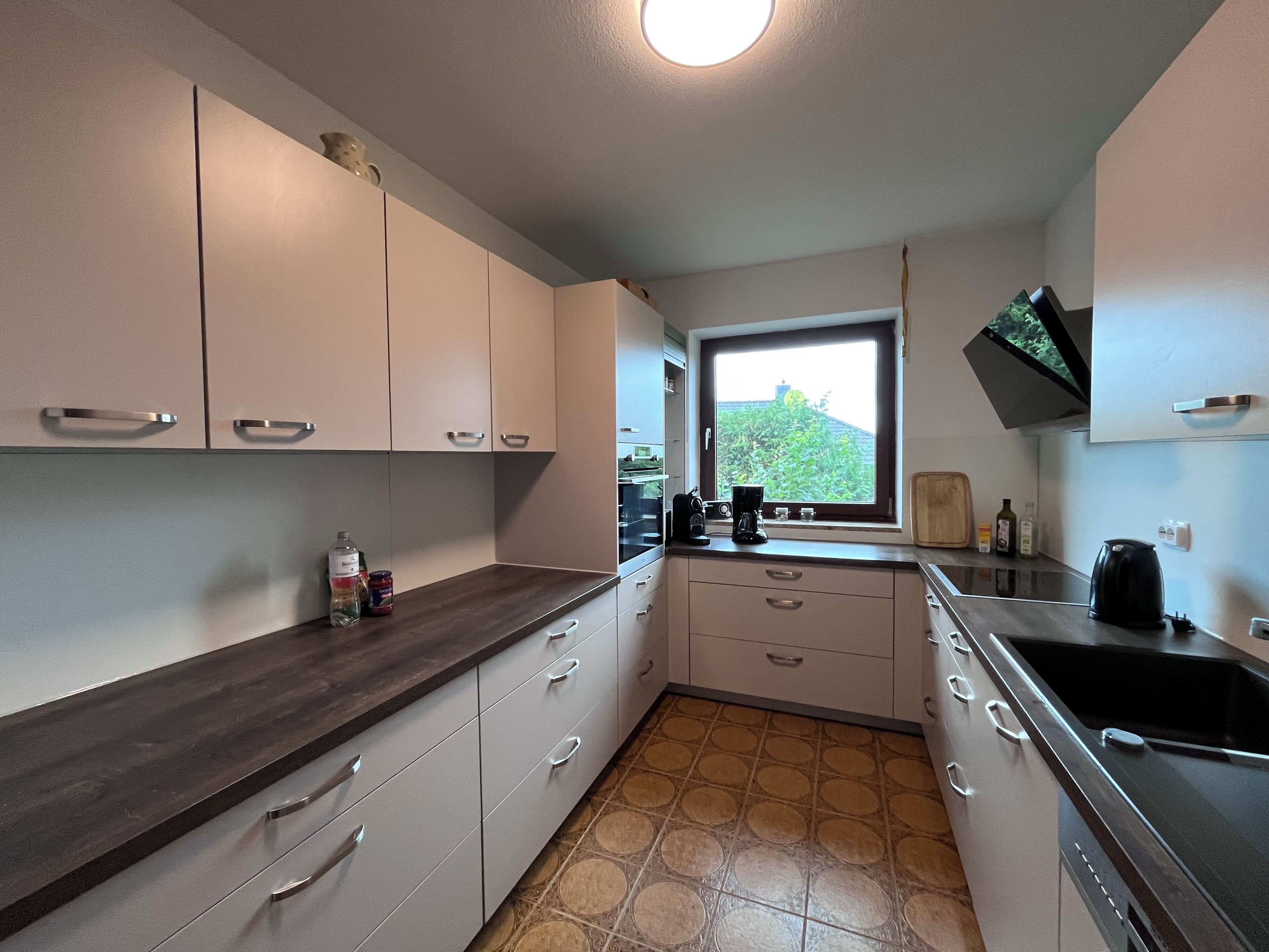 A kitchen with white cabinets, a dark countertop, a window with a view, and a stove.