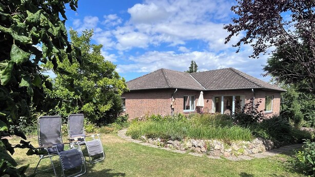 A brick house with a tiled roof, a grassy yard, and a fire pit. - Mühlenberg Vacation Home (Grebin)