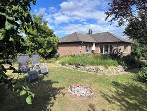 A brick house with a tiled roof, a grassy yard, and a fire pit. - Mühlenberg Vacation Home (Grebin)