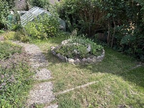 A garden with a stone border, a pathway, and dense foliage. - Mühlenberg Vacation Home (Grebin)