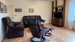 A living room with two leather sofas, a flat-screen TV, and a wooden cabinet with decorative items. - Mühlenberg Vacation Home (Grebin)