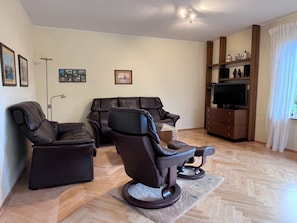 Ein Wohnzimmer mit zwei Ledersofas, einem Flachbildfernseher und einer Holzkabine mit Dekoration.