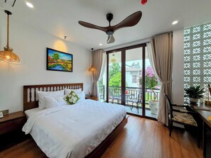 Een hotelkamer met een bed, een plafondventilator, een schilderij en uitzicht.