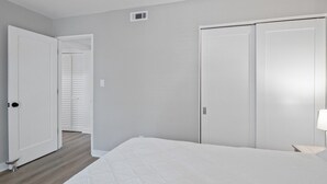 Une chambre à coucher avec un lit, deux portes et une table de chevet avec une lampe.