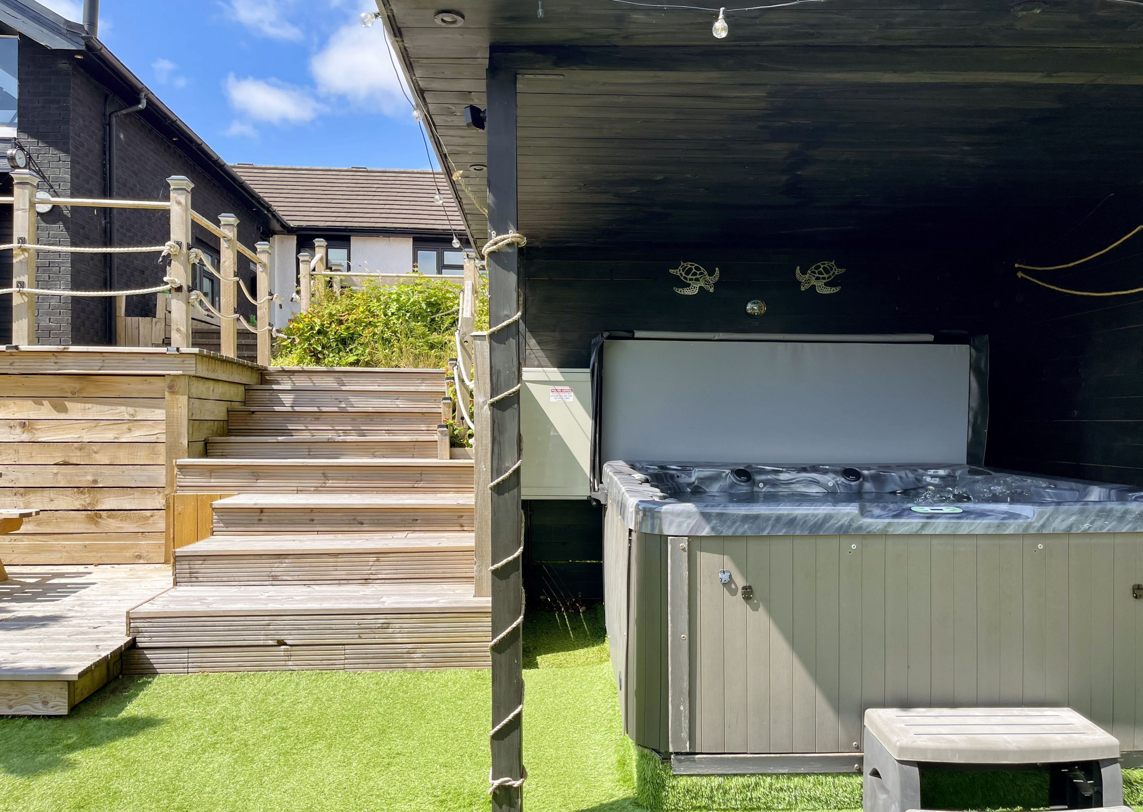 A hot tub with a wooden deck and steps leading to a covered area.