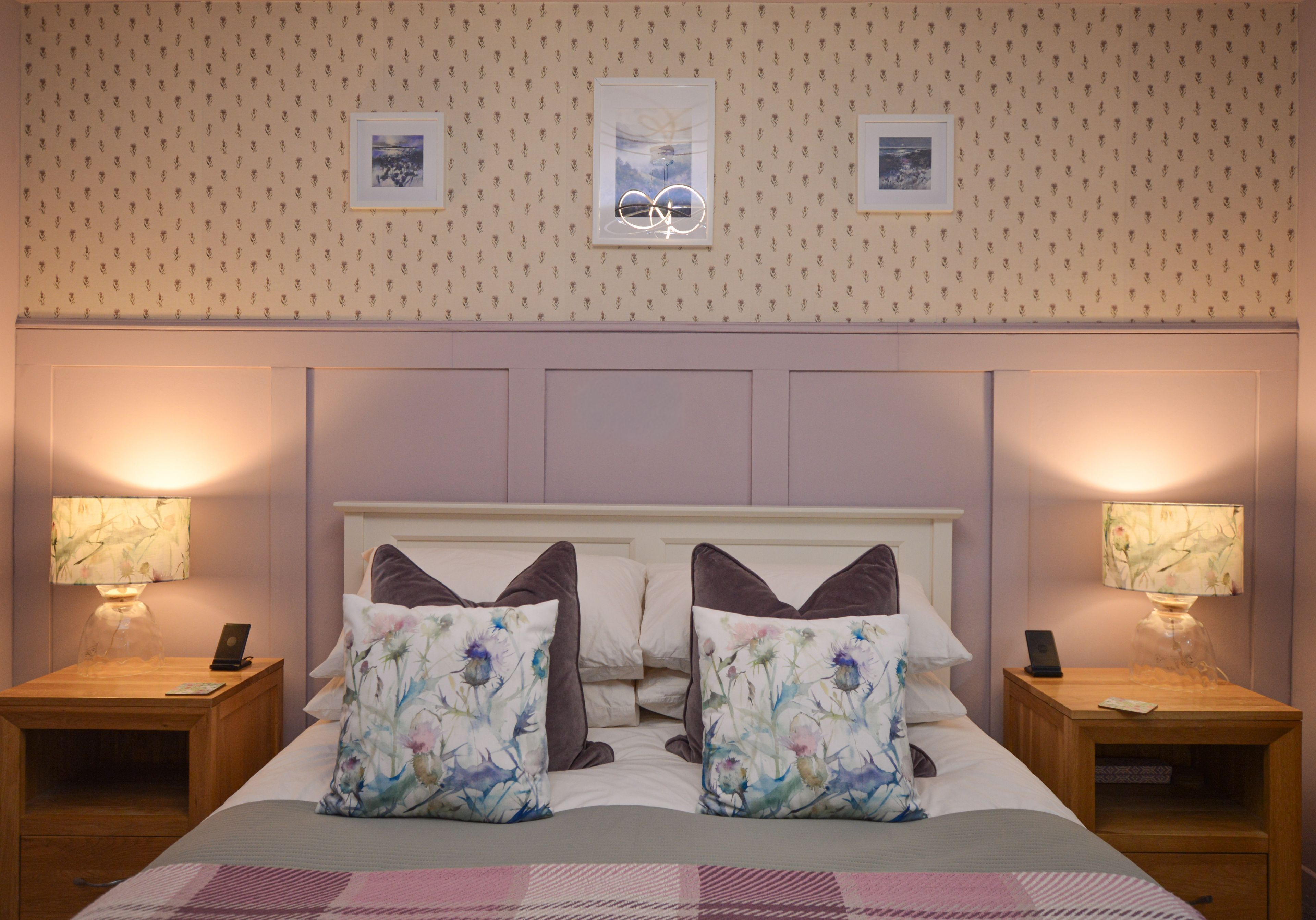 A hotel room with a large bed, two bedside tables, and a headboard with a floral pattern.