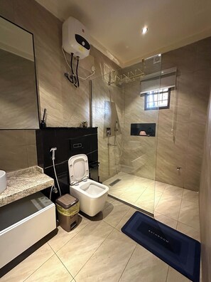 Ein modernes Badezimmer mit einer Duschkabine, einer Toilette, einem Waschbecken und einem Spiegel.