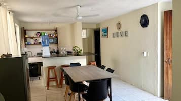 A compact kitchen with a dining area, a water dispenser, and a 'LIVE' sign on the wall.