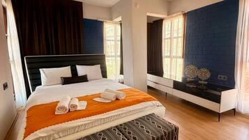 Habitación de hotel con cama, reposabajares y ventilador de techo, ofreciendo vista al exterior.