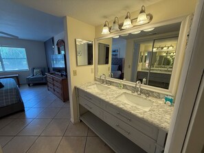 Un baño con lavamanos doble, tocador y un espejo grande con iluminación.