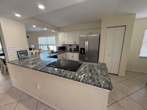 A modern kitchen with a granite countertop, stainless steel appliances, and white cabinetry. - Sunny 2BR Condo w/ Heated Pool — Minutes to IMG Academy & Beaches (Bradenton)