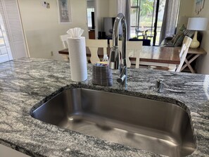 Eine Küche mit einer Arbeitsplatte aus Granit, einer Spüle aus Edelstahl und einem modernen Wasserhahn.