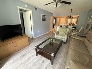 Ein Wohnzimmer mit Fernseher, Couchtisch, Sofa und Deckenventilator.