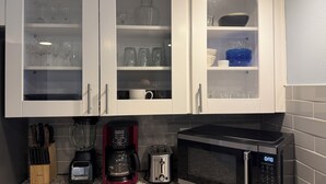 Una cocina con armarios blancos, cafetera, tostadora y microondas.