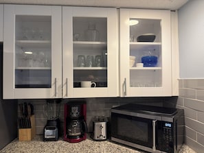 Eine Küche mit weißen Schränken, einer Kaffeemaschine, einem Toaster und einer Mikrowelle.
