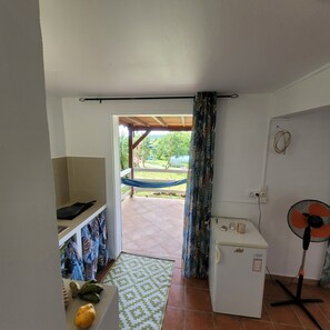 Eine kleine Küche mit Kühlschrank, Ventilator und einer Essecke.