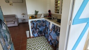 A kitchen with a patterned backsplash, a sink, and a window with blinds. - Sofaia Studio: Quiet, relaxing garden view, 2 km from the sulfur baths of Sofaia (Sainte-Rose)