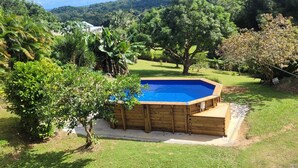 A wooden hot tub in a backyard with a pool, surrounded by lush greenery and trees. - Sofaia Studio: Quiet, relaxing garden view, 2 km from the sulfur baths of Sofaia (Sainte-Rose)