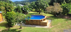 A wooden hot tub in a backyard with a pool, surrounded by lush greenery and trees. - Sofaia Studio: Quiet, relaxing garden view, 2 km from the sulfur baths of Sofaia (Sainte-Rose)