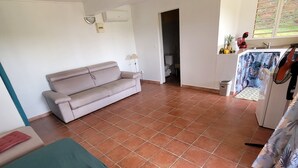 A living room with a sofa, a dining area with a table and chairs, and a kitchen with a sink and counter. - Sofaia Studio: Quiet, relaxing garden view, 2 km from the sulfur baths of Sofaia (Sainte-Rose)