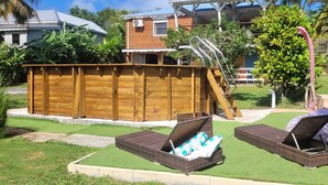 A backyard with a wooden deck, a small pool, and two wicker lounge chairs. - Sofaia Studio: Quiet, relaxing garden view, 2 km from the sulfur baths of Sofaia (Sainte-Rose)