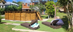A backyard with a wooden deck, a small pool, and two wicker lounge chairs. - Sofaia Studio: Quiet, relaxing garden view, 2 km from the sulfur baths of Sofaia (Sainte-Rose)