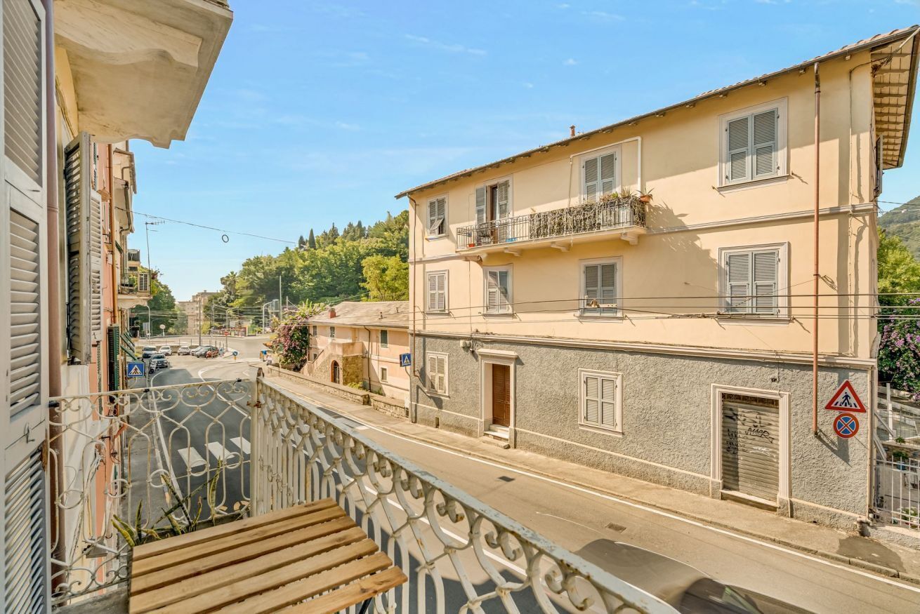 Een woonstraat met een balkon, een gebouw met een balkon, en een voetgangersoversteekplaats bord.