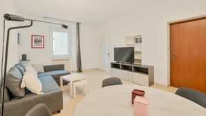 Een moderne woonkamer met een bank, een salontafel, een televisie en een boekenkast.