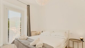 Een slaapkamer met een groot bed, een nachtkastje, een raam met uitzicht en een kroonluchter.
