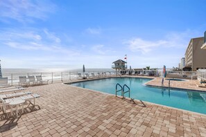 A pool area with lounge chairs and a lifeguard tower. - Dimucci Towers Ten 1901 (Daytona Beach Shores)