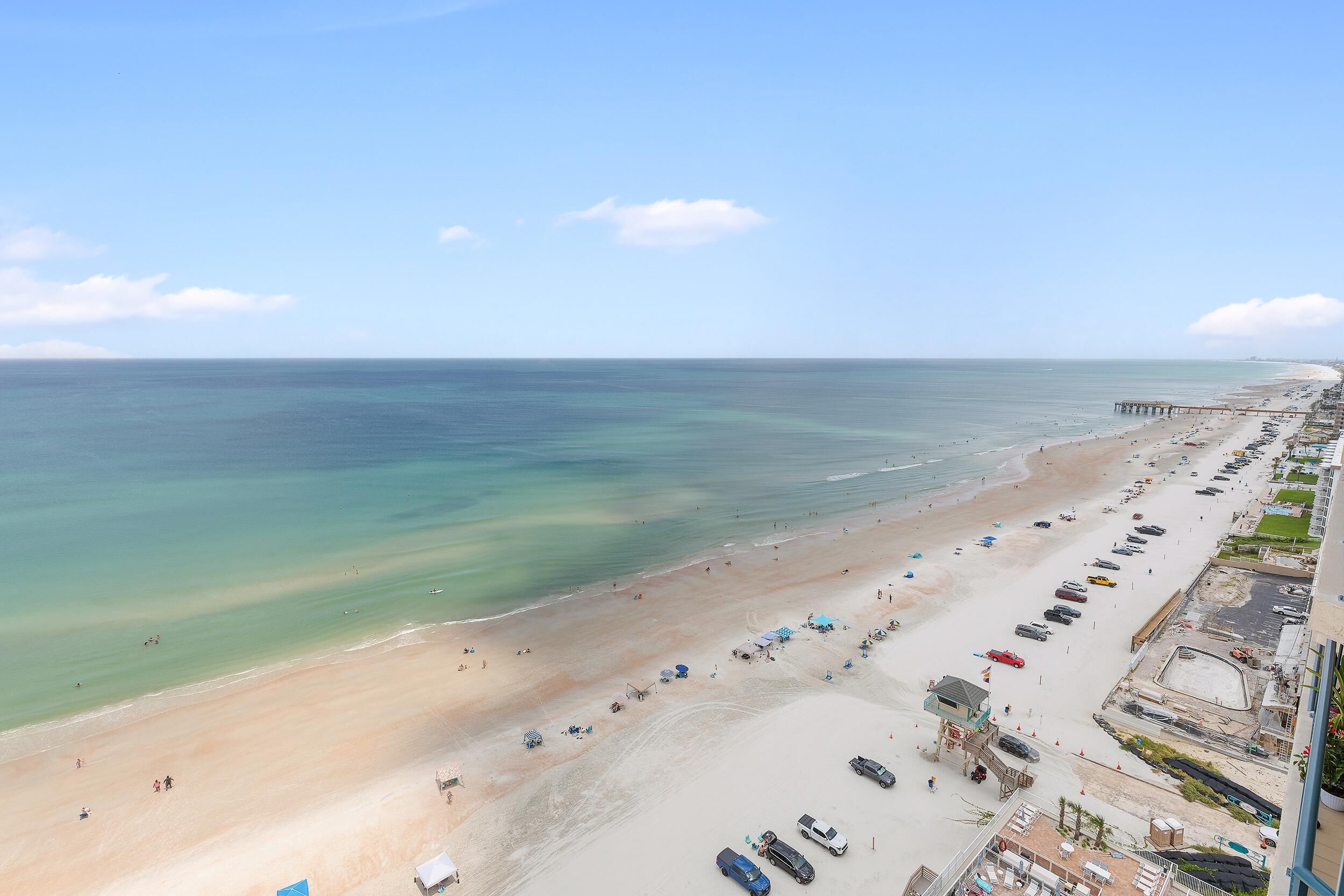 Ein Strand mit einem Steg, klarem Himmel und Blick auf den Ozean.