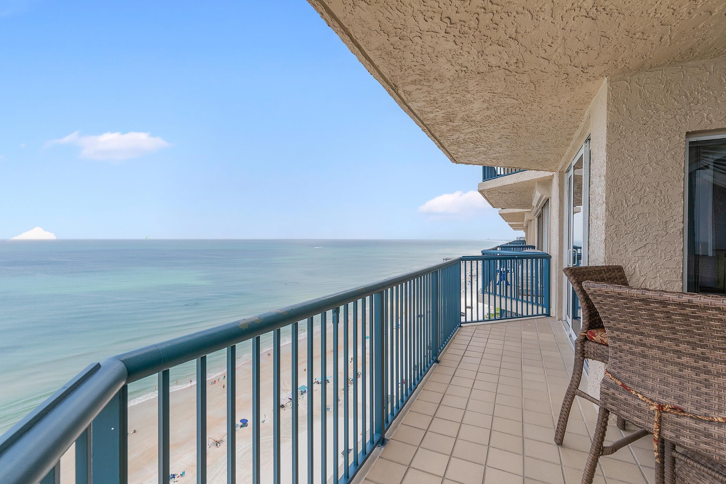 A balcony with a view of the beach and ocean.