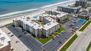 A beachfront hotel with multiple buildings, a parking lot, and a swimming pool. - Castle Reef 527 (New Smyrna Beach)